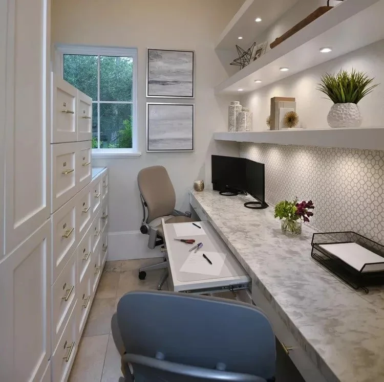 Small home office with layered lighting, including shelf lights, recessed lights, and natural light from a window. Well-lit and organized workspace.